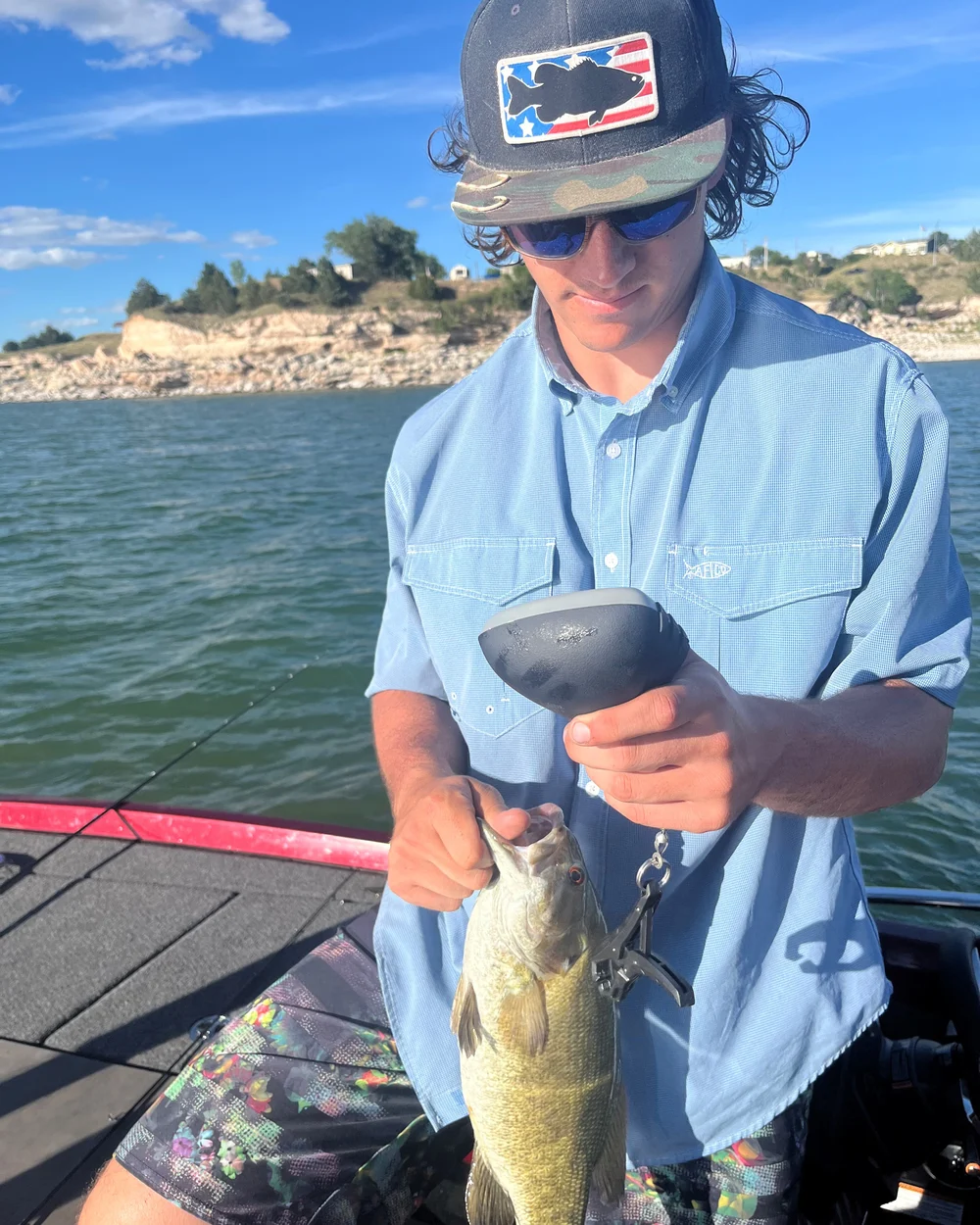 A young man weighing a bass after catching it with a swimbait